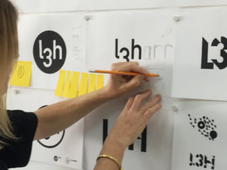 Kat marks up some logos on the wall for L3Harris